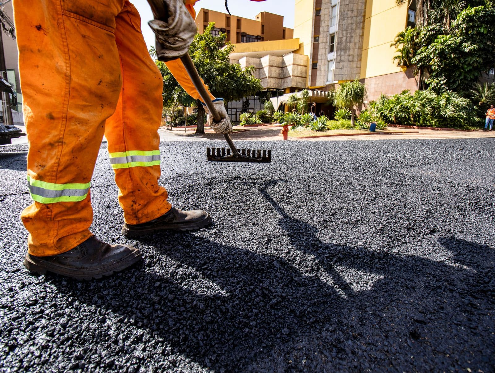 Asphalt paving crew member raking fresh hot-mix asphalt on a street resurfacing job